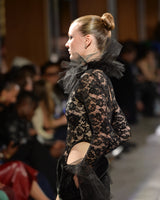 Model wearing a black lace top with sheer details on a runway Faux fur narces mini skirt runway shot
