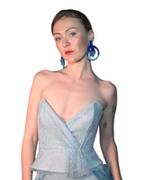 A model wearing a strapless light blue mesh corset-style top with a sweetheart neckline and a knotted waist detail, paired with large blue hoop earrings, against a plain white background.